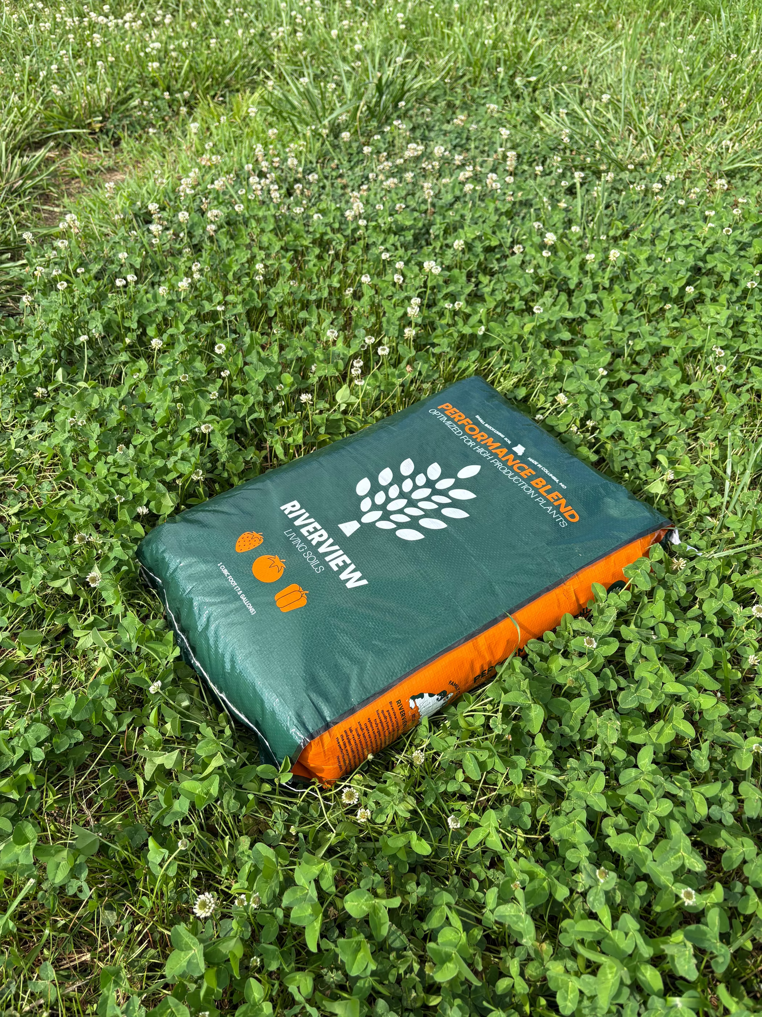 Green and orange Performance Blend soil bag with Riverview Living Soils Logo on grass